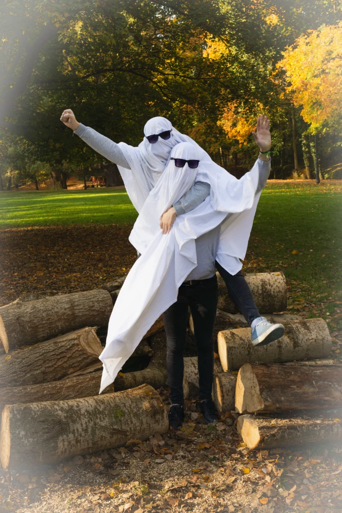 Dwie osoby ubrane w prześcieradła z okularami przeciwsłonecznymi, udające duchy